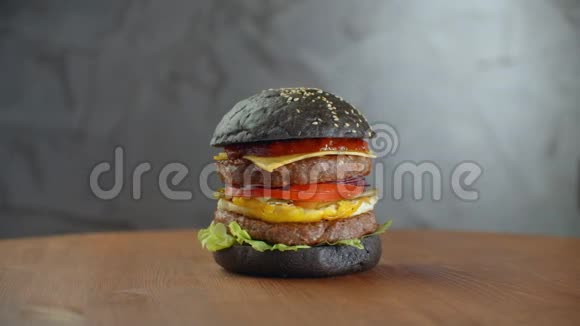 黑汉堡一个汉堡里面有一个黑卷切片多汁的大理石牛肉融合奶酪新鲜沙拉和烤肉酱视频的预览图