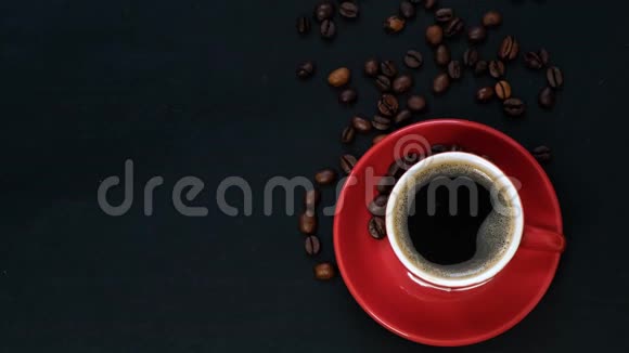 红色杯子中的深色咖啡和黑色桌子上的咖啡豆带有复制空间顶部视图视频的预览图