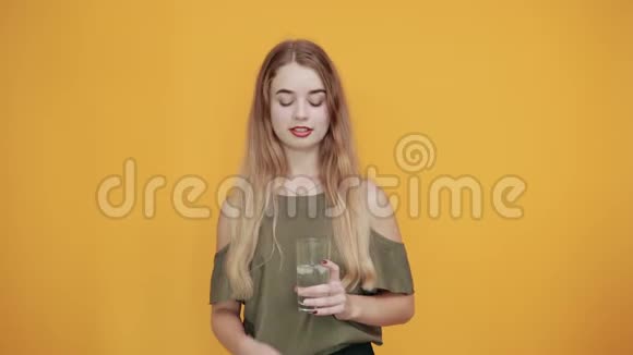 年轻的金发女郎穿着休闲服装端着一杯水视频的预览图