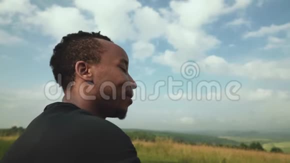 微笑的非洲男人在山顶欣赏风景如画的景色视频的预览图