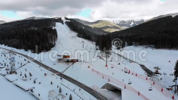 冬季滑雪场有滑雪者和滑雪升降机的滑雪斜坡的空中景观视频的预览图