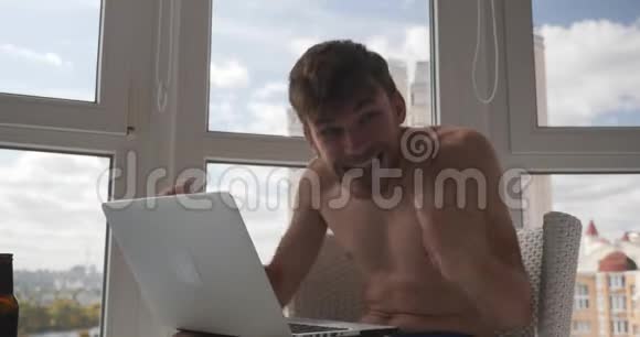 快乐快乐的白种人男性游戏玩家穿着内裤在笔记本电脑上玩并赢得了网络游戏举起双手高兴起来视频的预览图