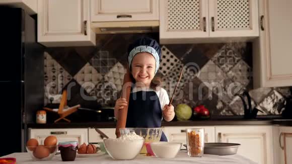 手里拿着擀面杖的小女孩正在厨房里准备蛋糕视频的预览图