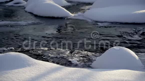 在冉冉升起的阳光下森林河岸上的雪堆视频的预览图
