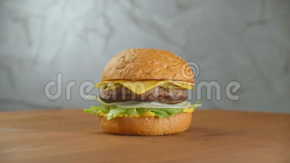 一个汉堡包在一块板上炸薯条散落一地特写美味的新鲜自制汉堡配生菜奶酪视频的预览图