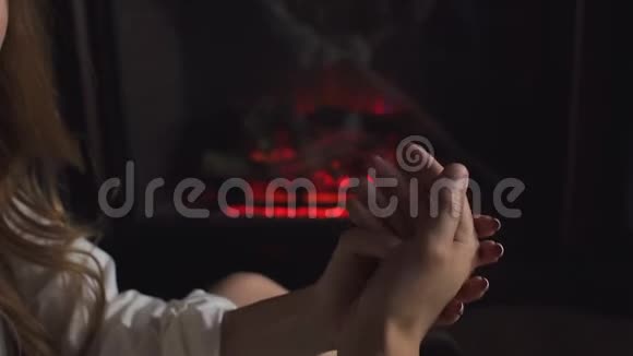 一对夫妇的特写在燃烧的壁炉的背景上轻轻地牵手视频的预览图