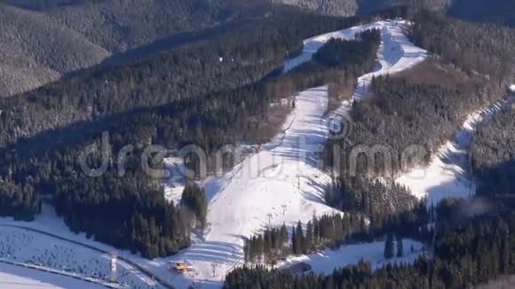 滑雪者在阳光明媚的一天在滑雪场的雪坡上骑马视频的预览图
