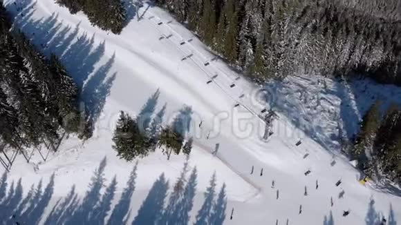 雪域森林滑雪场上有滑雪者和滑雪升降机的空中滑雪斜坡视频的预览图