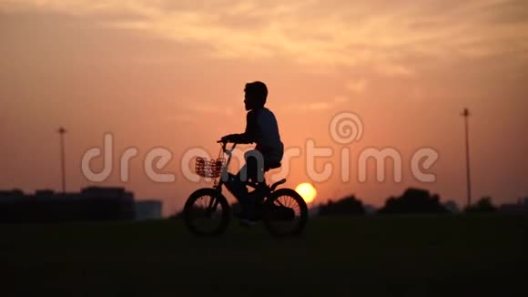 日落时骑自行车慢动作的小孩剪影视频的预览图