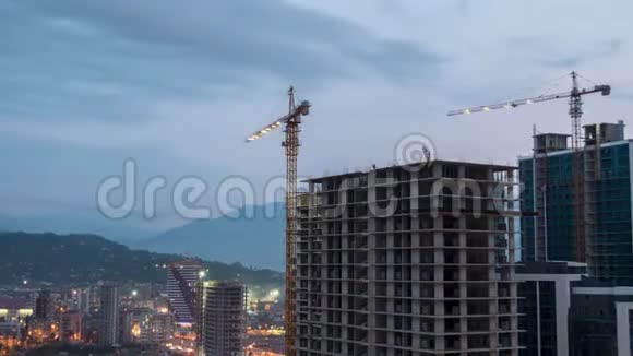 建筑施工从白天到晚上时光流逝建筑工地配备照明的塔式起重机视频的预览图
