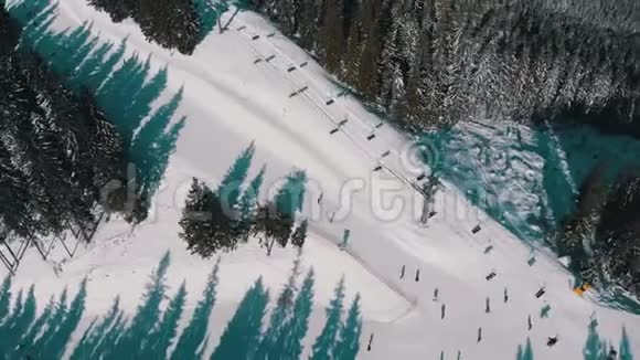 雪域森林滑雪场上有滑雪者和滑雪升降机的空中滑雪斜坡视频的预览图