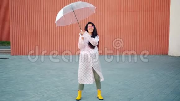 穿着雨衣穿着橡胶靴带着雨伞跳舞的慢动作视频的预览图