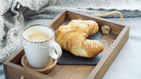 用咖啡和牛角面包从托盘中取出杯子的女性手在床上吃早餐视频的预览图