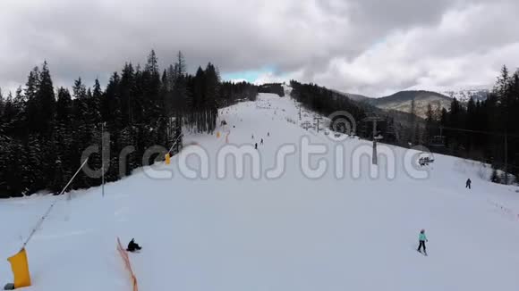 冬季滑雪场有滑雪者和滑雪升降机的滑雪斜坡的空中景观视频的预览图