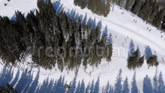 雪域森林滑雪场上有滑雪者和滑雪升降机的空中滑雪斜坡视频的预览图