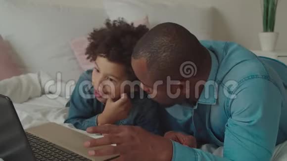 父亲带着孩子上网浏览笔记本电脑视频的预览图