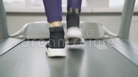 在健身房的跑步机上穿着运动鞋的女性腿视频的预览图