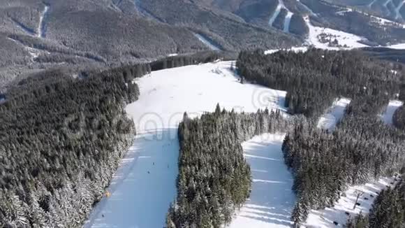 在滑雪场设有滑雪者和滑雪升降机的空中滑雪斜坡雪山森林视频的预览图