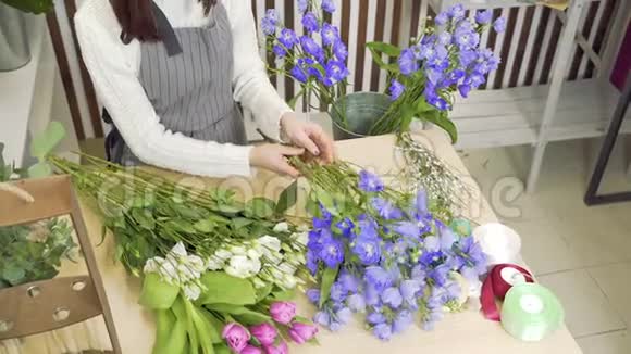 年轻的女花匠在车间或花店里检查和挑选最好的花束视频的预览图