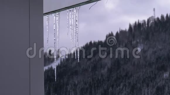 冰柱融化滴在屋顶上春天的蓝天背景视频的预览图