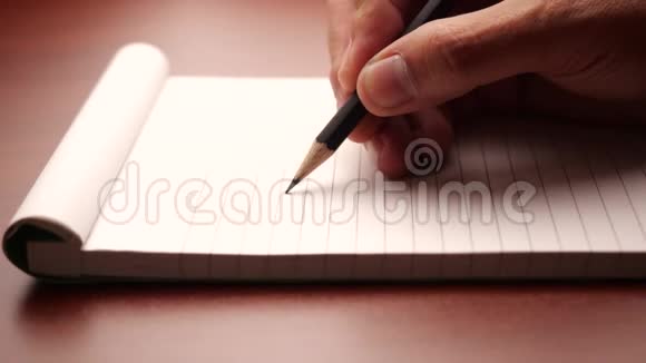 用铅笔写在笔记本上的男性手在家庭办公室工作的男性视频的预览图