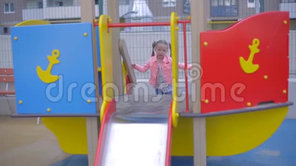 穿牛仔裤的金发小女孩在儿童公园玩耍视频的预览图