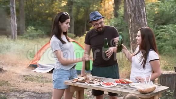 休闲和人的概念快乐的朋友在森林里举杯喝酒在日落时带帐篷的夏日派对视频的预览图