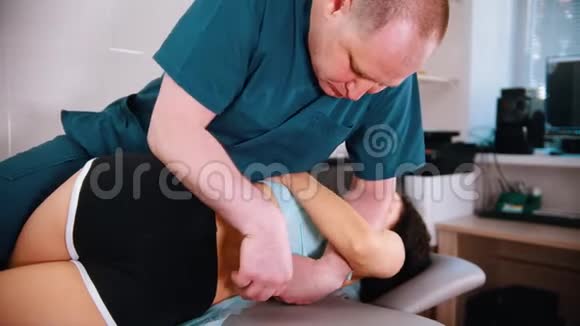 脊椎按摩治疗医生把女人移到一边压在她的背上锻炼脊柱视频的预览图