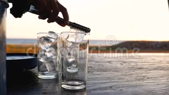 夏天把冰夹在透明的玻璃上放在海边的木桌上视频的预览图