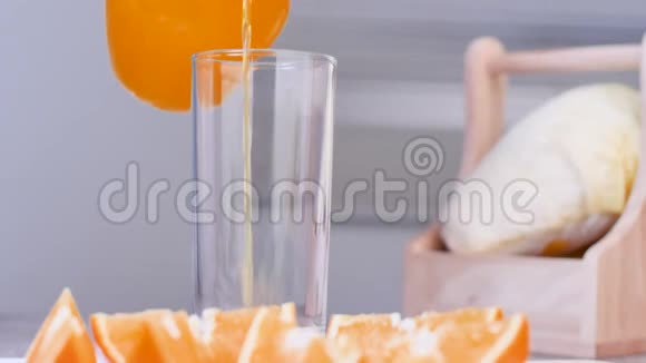 特写把橙汁倒在桌子上的透明玻璃杯里模糊的前景是橙子片视频的预览图