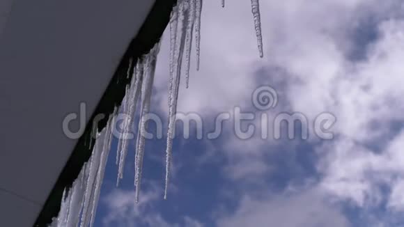 冰柱融化滴在屋顶上春天的蓝天背景视频的预览图