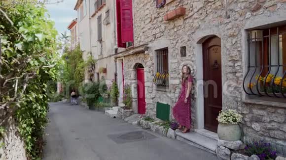 法国浪漫城市古石屋红门前站着一位身着红色圆点裙的漂亮姑娘视频的预览图