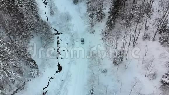 在神奇的冬林中乘雪路上的孤独汽车上的鸟瞰视频的预览图