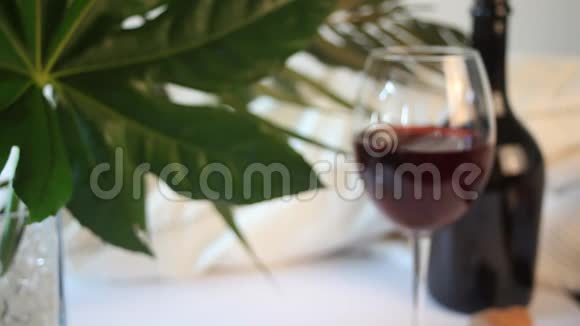 女人手里放了一杯红酒背景上的瓶子浪漫的晚餐概念视频的预览图