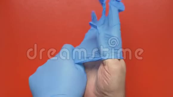 医生在红色背景上戴上蓝色无菌手术手套特写镜头概念流行病保险视频的预览图