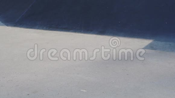 黑滑板在阳光明媚的日子骑在水泥滑板公园里视频的预览图