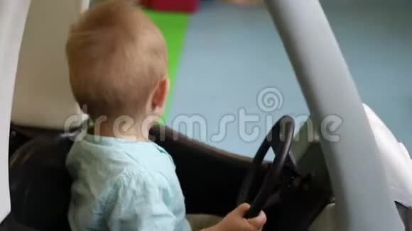 坐在玩具车里的男孩婴儿关上车门开车儿童游戏中心视频的预览图