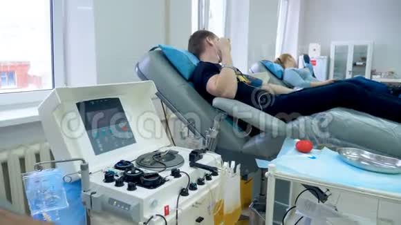 人们坐在医疗椅上在诊所献血视频的预览图