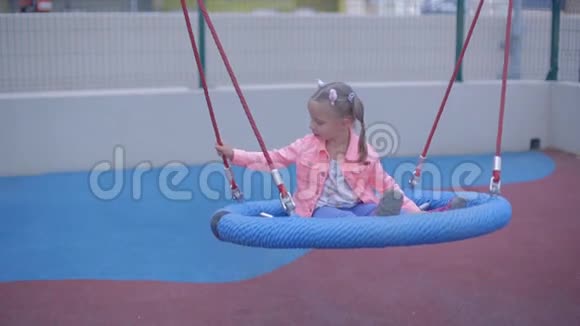 穿牛仔裤的金发小女孩在儿童公园玩视频的预览图