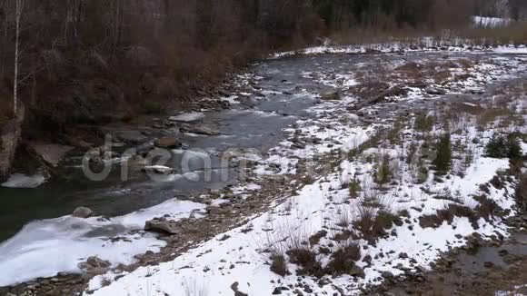 冬天的山溪在冬天的风景中山河流过冰雪靠近岩石视频的预览图
