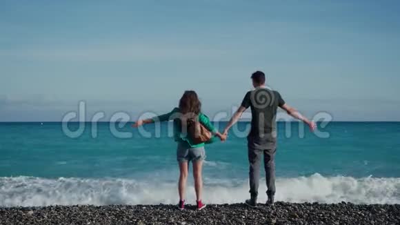 年轻活泼的一对随意的夫妇正站在海边手牵手欣赏着无尽的景色视频的预览图
