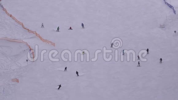 在阳光明媚的日子里滑雪者和滑雪者在滑雪场的雪坡上骑行视频的预览图
