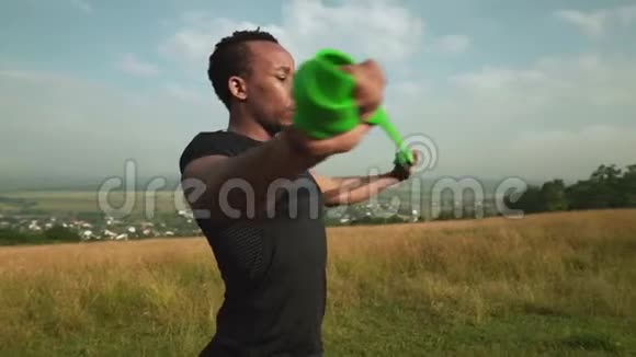 非洲男人用橡胶扩张器锻炼身体的侧视视频的预览图