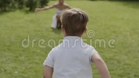 一个穿着白色衣服的小男孩跑向他心爱的妈妈妈妈抱着儿子视频的预览图
