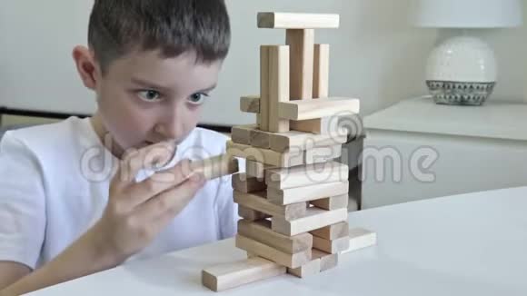 一个十几岁的白种人男孩用木块制作塔他集中精力全神贯注儿童玩游戏视频的预览图