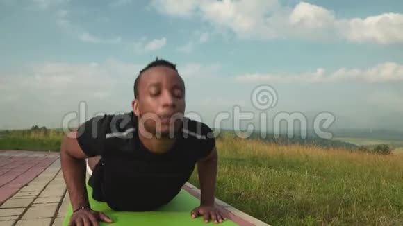 运动非洲男子伸展躯干在瑜伽垫自然视频的预览图