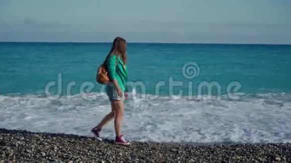 美丽的年轻女子在法国尼斯市的海边身穿绿色夹克和牛仔短裤的卷发后视图视频的预览图