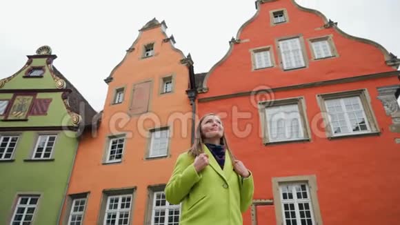 旅游女孩或穿黄色外套的学生带着背包看着老城市场上的传统房子视频的预览图