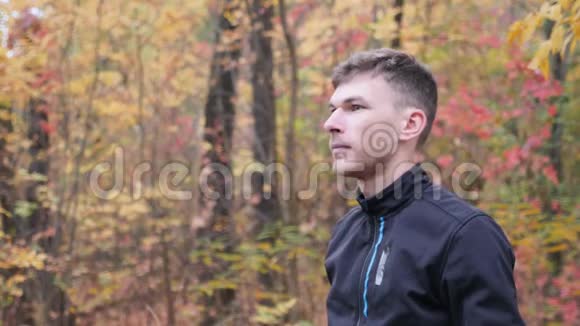 秋天公园里的男自行车手侧面的肖像年轻职业自行车运动员戴上黑色头盔自行车的概念慢动作视频的预览图