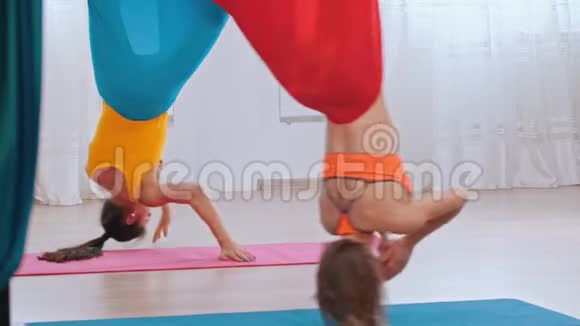 空中瑜伽两个女人倒吊在吊床上做瑜伽蝙蝠姿势视频的预览图